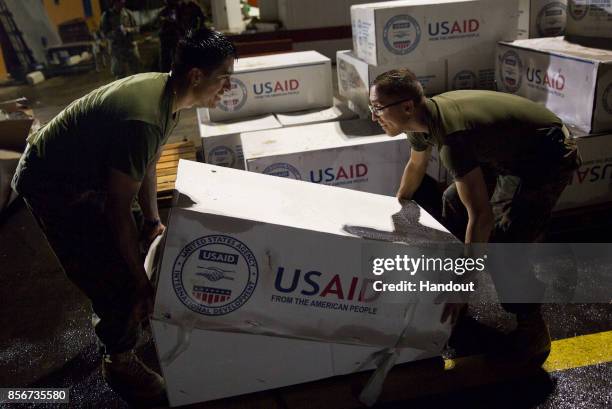 In this U.S. Navy handout, U.S. Marines assigned to Joint Task Force - Leeward Islands stack boxes of tarps from the U.S. Agency for International...