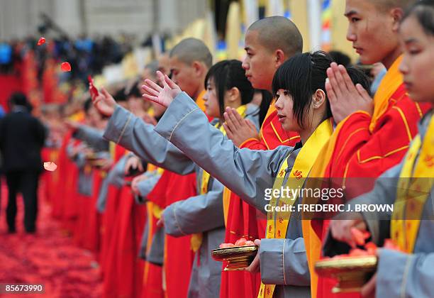 Volunteers toss rose petals while standing beside Buddhist monks welcoming arrivals for the opening session of the World Buddhist Forum on March 28,...