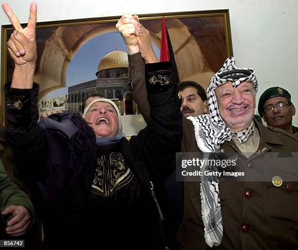 Palestinian leader Yasser Arafat holds hands with a chanting Arab woman during a support rally February 12, 2002 at his headquarters in the West Bank...