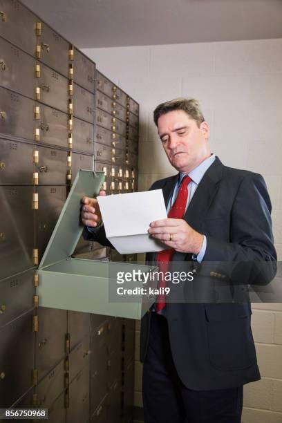 businessman opening a safety deposit box - safe deposit box stock pictures, royalty-free photos & images