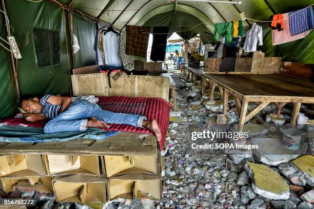 Man is seen resting in one of the makeshift tents in the Pasar Ikan neighborhood of Jakarta. In April last year hundreds of soldiers and police...