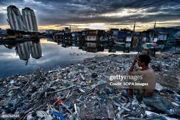 Man is seen sitting on the ruins of what was the neighborhood of Pasar Ikan in Jakarta. In April last year hundreds of soldiers and police stormed...