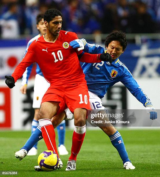 Hideo Hashimoto of Japan and Mohamed Salmeen of Bahrain compete for the ball during the 2010 FIFA World Cup Asian qualifier match between Japan and...