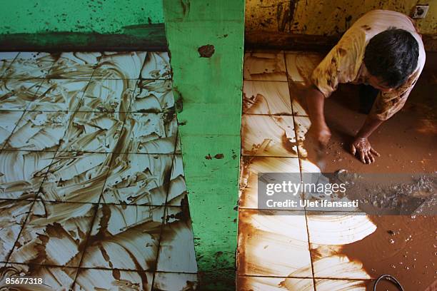 Man cleans his house after dam-burst on March 28, 2009 in Ciputat, Indonesia. As the official death toll rises to 77, Indonesian rescuers continue to...