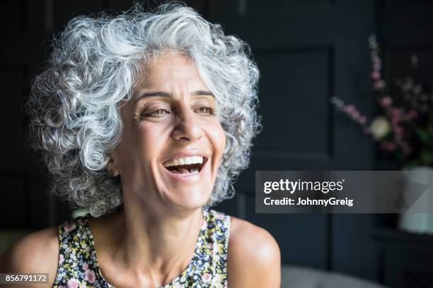 frau mit grauen lockiges haar wegsehen und lachen - gray hair stock-fotos und bilder