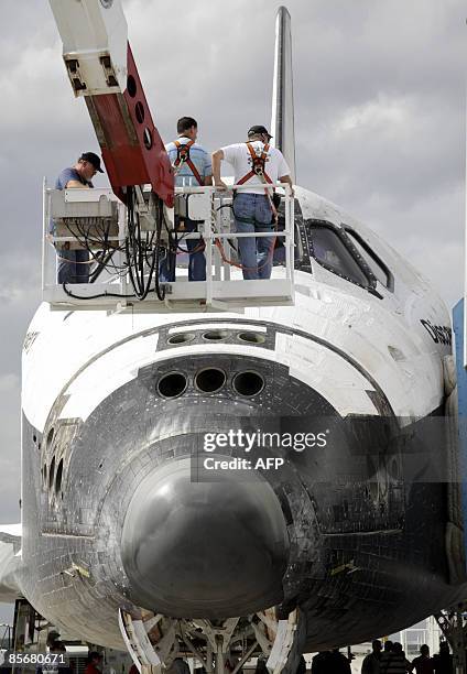 Ground crew members approach the nose of US space shuttle Discovery after it landed on March 28, 2009 at Kennedy Space Center in Florida, completing...