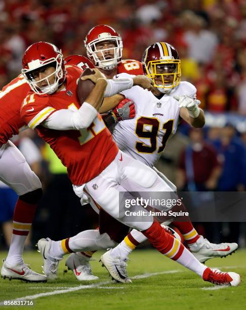 Quarterback Alex Smith of the Kansas City Chiefs falls to the ground as he is persued by outside linebacker Ryan Kerrigan of the Washington Redskins...