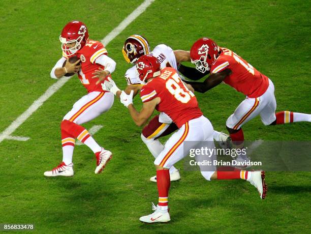 Quarterback Alex Smith of the Kansas City Chiefs is chased by outside linebacker Ryan Kerrigan of the Washington Redskins during the game at...