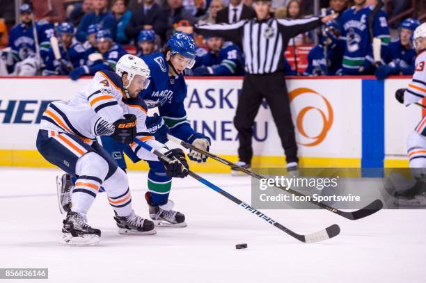Vancouver Canucks defenseman Ben Hutton defends against Edmonton Oilers defenseman Kris Russell during their NHL preseason game at Rogers Arena on...