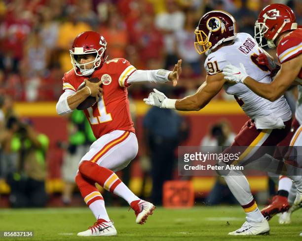 Quarterback Alex Smith of the Kansas City Chiefs is chased by outside linebacker Ryan Kerrigan of the Washington Redskins during the game at...