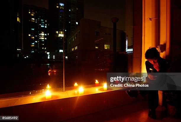 Man sits beside candles at a community's clubhouse on March 28, 2009 in Beijing, China. About 20 Chinese cities joined a WWF worldwide initiative...