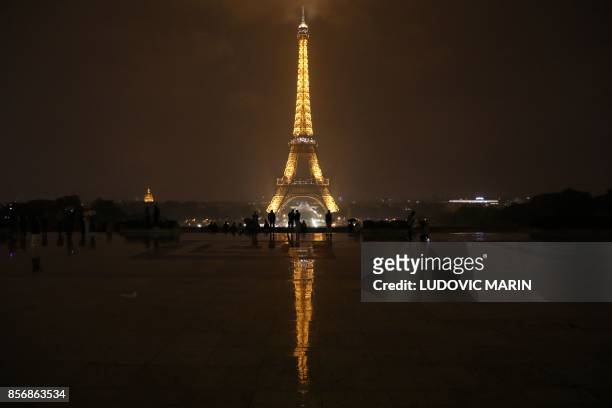 The Eiffel Tower is pictured in Paris before switching off lights on October 2, 2017 in tribute to the victims of the attacks in Las Vegas and...
