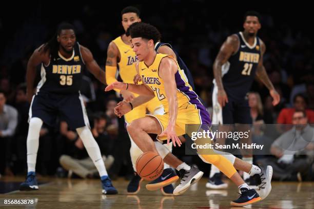 Lonzo Ball of the Los Angeles Lakers dribbles the ball as Kenneth Faried and Wilson Chandler of the Denver Nuggets defend during the first half of a...