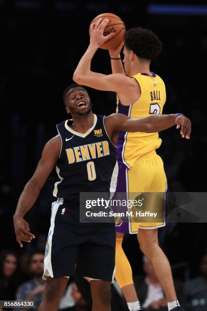 Lonzo Ball of the Los Angeles Lakers rebounds past Emmanuel Mudiay of the Denver Nuggets during the first half of a preseason game at Staples Center...