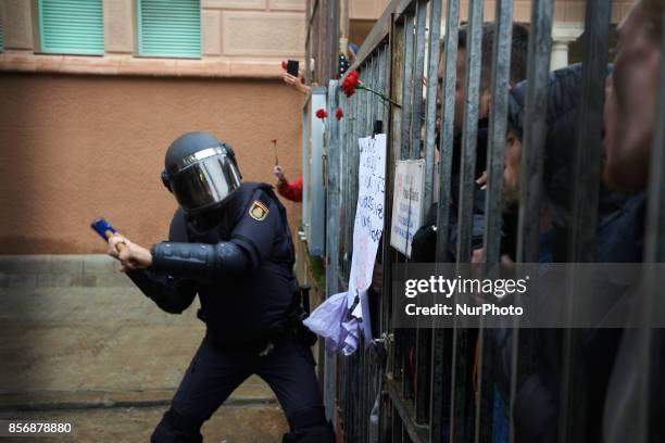 Spanish State Police officer uses a malllet to break in the IES Pau Claris polling station as voters show carnations in sign of peace. Spanish State...