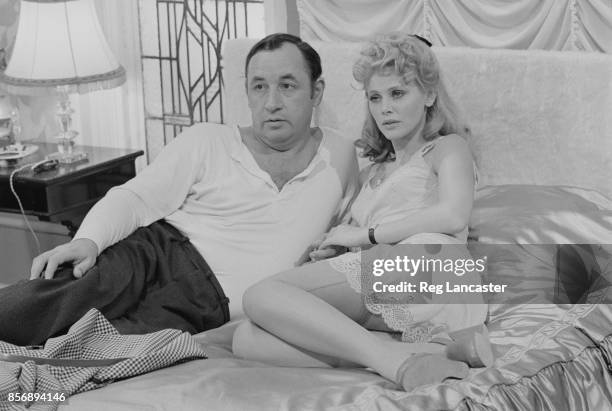 Swedish actress and singer Britt Ekland and French actor Philippe Noiret sit on a bed together on the set of British comedy-drama film 'A Time for...