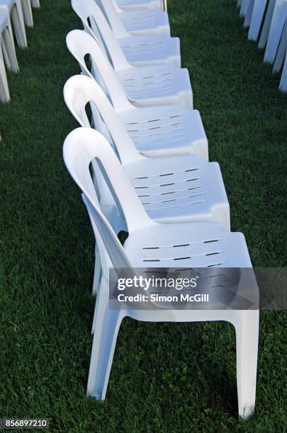 row of empty white plastic chairs arranged in readiness for an outdoor event - white plastic lawn chairs stock pictures, royalty-free photos & images