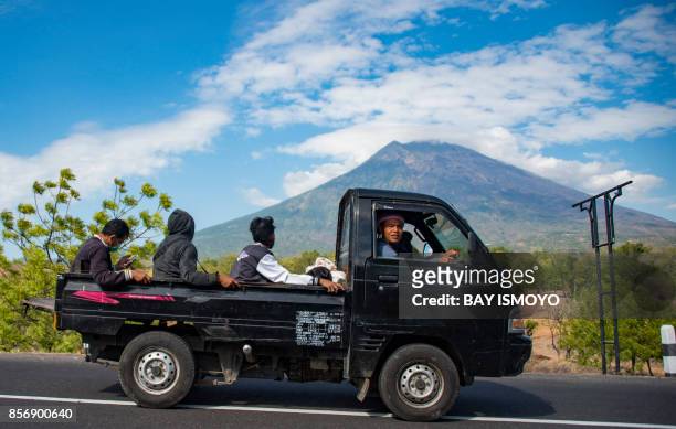 Balinese travel by a light truck in Karangasem, on Bali island on October 3 as Mount Agung volcano is seen in the background. Thousands of residents...