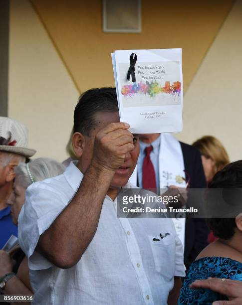 Man holds up a booklet during a vigil at Guardian Angel Cathedral for the victims of the Route 91 Harvest country music festival shootings on October...