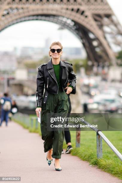 Vika Gazinskaya wears a black leather jacket, a green top, green pants, outside Hermes, during Paris Fashion Week Womenswear Spring/Summer 2018, on...