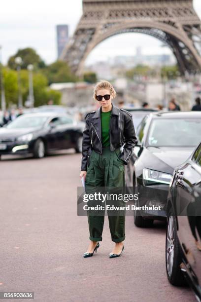 Vika Gazinskaya wears a black leather jacket, a green top, green pants, outside Hermes, during Paris Fashion Week Womenswear Spring/Summer 2018, on...