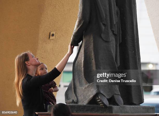 Woman touches a staue of the Blessed Mother Mary during a vigil at Guardian Angel Cathedral for the victims of the Route 91 Harvest country music...