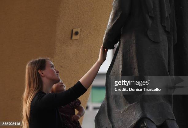 Woman touches a staue of the Blessed Mother Mary during a vigil at Guardian Angel Cathedral for the victims of the Route 91 Harvest country music...