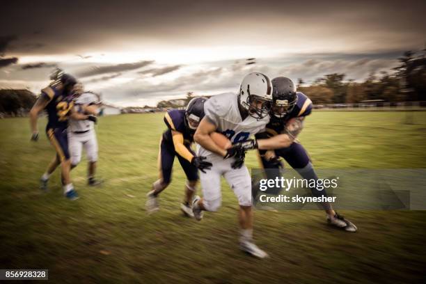 vastbesloten quarterback proberen te passeren verdedigende spelers op american football wedstrijd. - first down american football stockfoto's en -beelden