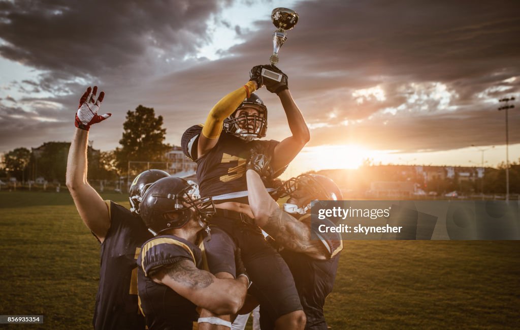 Team of American football players celebrating victory at sunset.