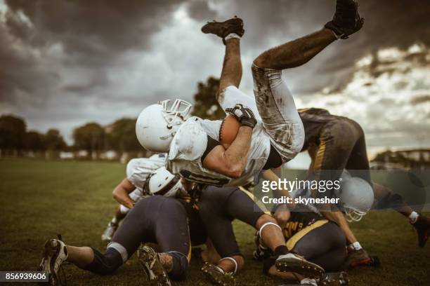 large group of american football players on a pile. - tackling stock pictures, royalty-free photos & images