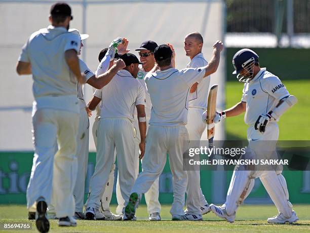 India's Sacin Tendulkar walks back to the dressing room after losing his wicket as New Zealand cricketers congratulate teammate Chris Martin for...