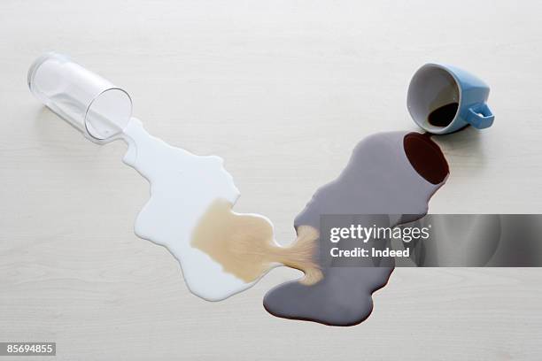 spilt milk combining with coffee on table - spilled drink stock pictures, royalty-free photos & images