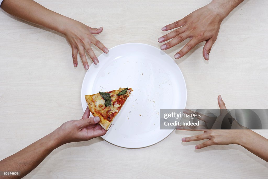 Men reaching last pizza from plate