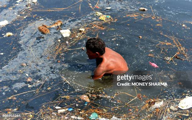 An Indian worker removes religious offerings and frames of the idol of goddess Durga which were immersed in the Yamuna river after the Durga Puja...