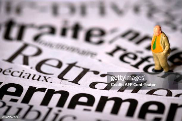 Photo prise le 19 juin 2013 à Paris, d'un personnage miniature photographié sur différentes coupures de journaux traitant du sujet de la réforme des...