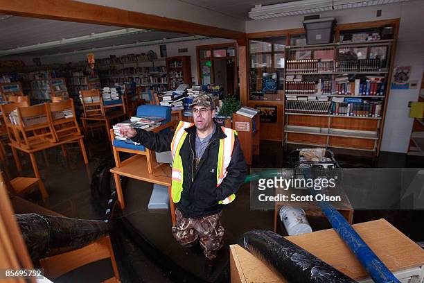 Pete Montplaisir sets up pumps to remove flood water from the library of Oak Grove Lutheran School after a levee break flooded the campus March 29,...