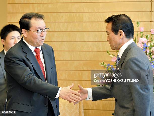 Li Changchun , standing committee member of Chinese Communist Party's Political Bureau, shakes hands with Japanese Prime Minister Taro Aso prior to...