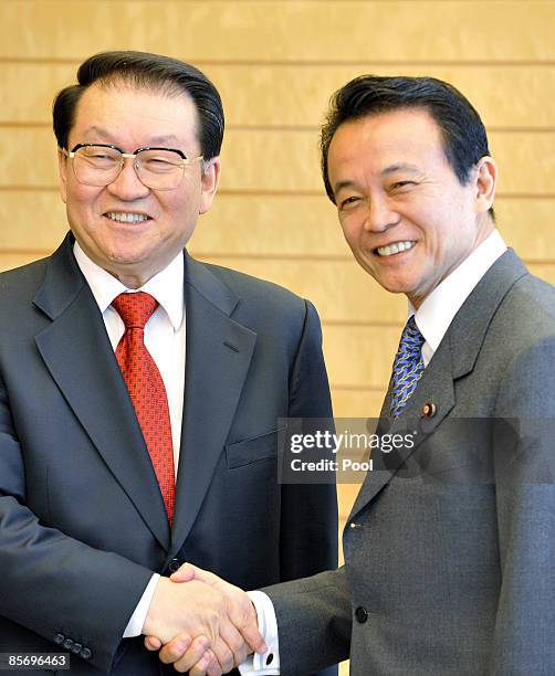 Li Changchun, a standing committee member of Chinese Communist Party's Political Bureau shakes hands with Japanese Prime Minister Taro Aso prior to...