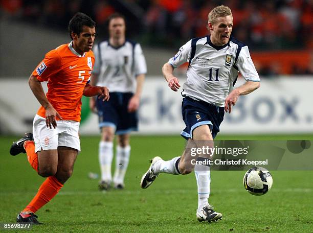 Barry Robson of Scotland runs with the ball and Giovanni van Bronckhorst of Netherlands follows him during the FIFA 2010 World Cup qualifying match...