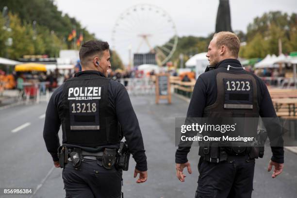 Two German policemen patrol an amusement area set up along 17th of June Street in Tiergarten Park near the Brandenburg Gate on German Unity Day on...