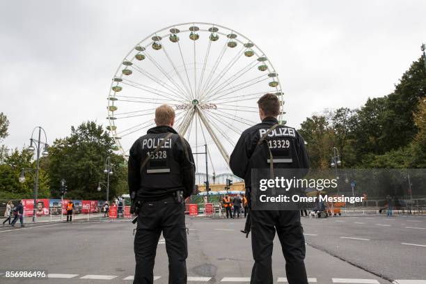 Two German policemen stand guard in front of a ferris wttheel near an amusement area set up along 17th of June Street in Tiergarten Park near the...