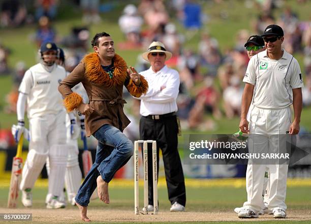 New Zealand cricketer Ross Taylor and others look on as a pitch invader runs through the ground during the third day of the second Test match at the...