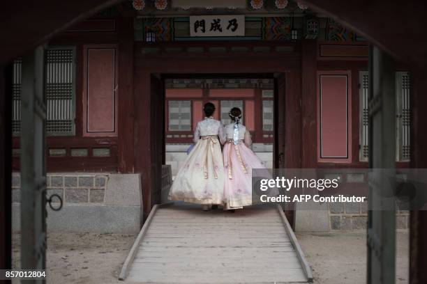 Women wearing traditional Korean hanbok dress walk through Gyeongbokgung palace in Seoul on October 3, 2017. South Korea is observing the annual...