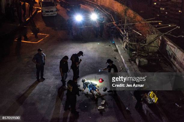 Police investigators inspect the body of John Estrella who was allegedly killed by unidentified assailants on June 26, 2017 in Manila, Philippines....