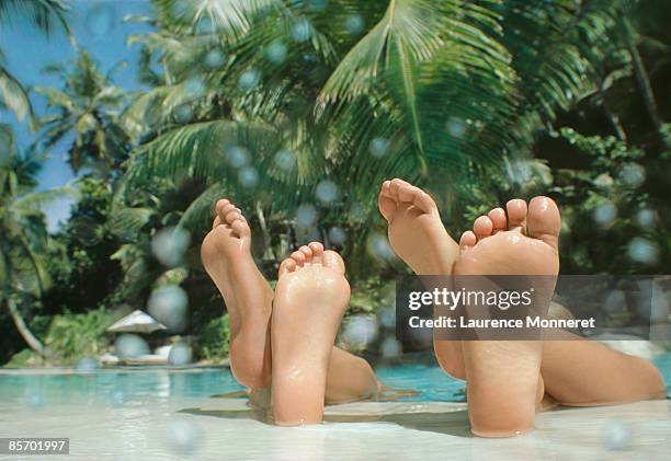kids crossed feet resting on a tropical pool edge - voetzool stockfoto's en -beelden