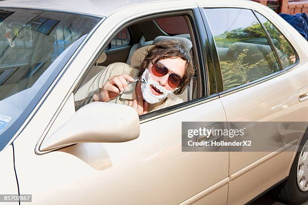 man sitting in car shaving - scheren stockfoto's en -beelden