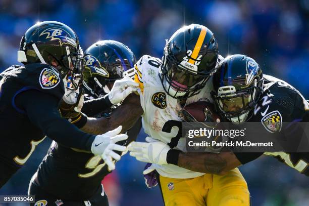 Running back Le'Veon Bell of the Pittsburgh Steelers is tackled by defensive end Za'Darius Smith and cornerback Jimmy Smith of the Baltimore Ravens...