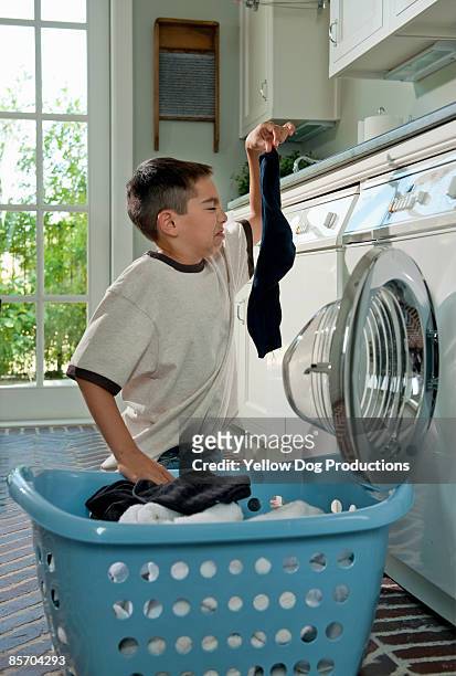 humorous picture of boy doing laundry chores - smelly laundry stock pictures, royalty-free photos & images