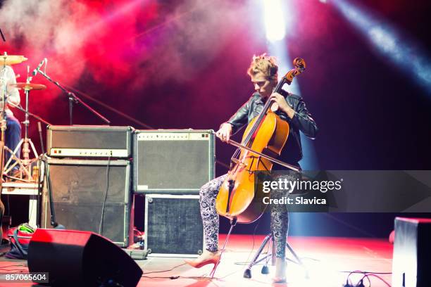 musicista donna che suona il violoncello sul palco sotto i riflettori - orchestra foto e immagini stock