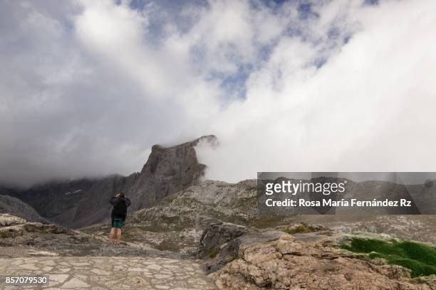 adult man watching through binoculars in the peaks of europe national park on a foggy day, comunidad autónoma de cantabría, spain, europe. - comunidad autónoma de cantabria stockfoto's en -beelden